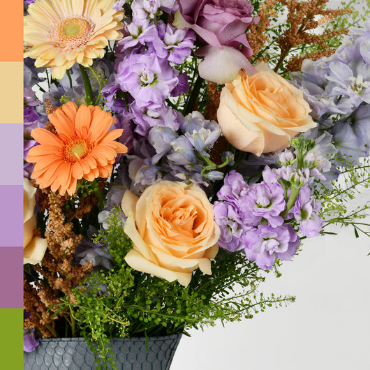 purple and peach flowers arrangement in grey leather vase