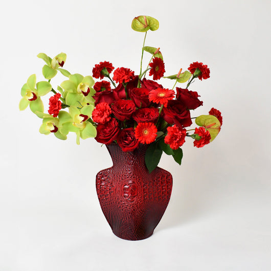 red and green flowers arrangement in red leather vase