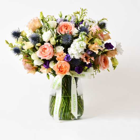 PEACH ROSES BLUE EUSTOMA SOLIDAGO AND WHITE FLOWERS ARRANGEMENT IN A VASE